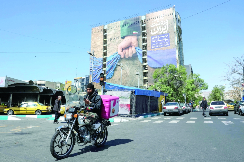 A man rides past a large billboard referring to the Strait of Hormuz in Tehran's Vanak Square. — AFP