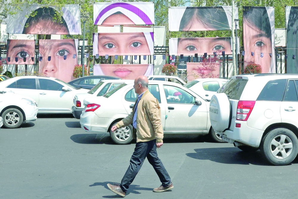 A man walks past the portraits of children killed in a deadly strike on a children's school in the southern city of Minab at the Tajrish Square in Tehran. 
- AFP