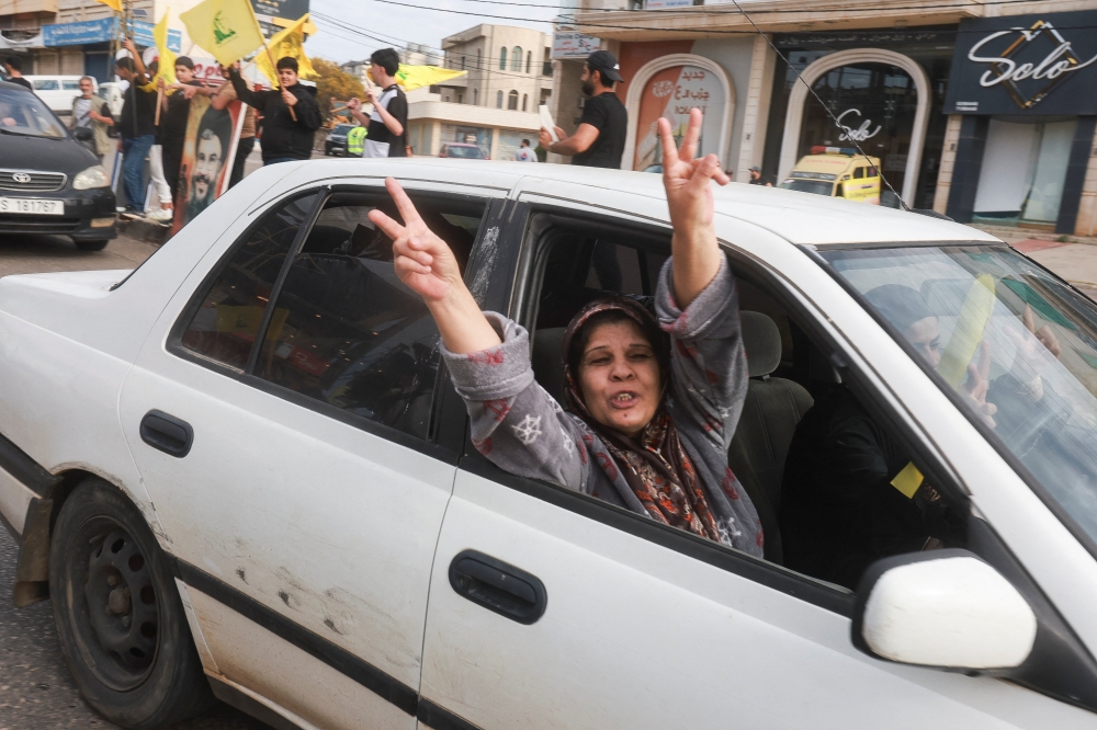 A woman in a car flashes the victory sign as displaced people return to their homes, after a 10-day ceasefire between Lebanon and Israel went into effect, near Nabatieh