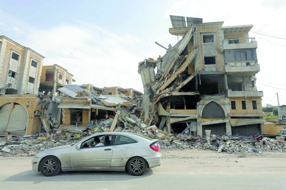 Displaced residents drive past a destroyed building as they return back to the southern Lebanese city of Nabatieh. — AFP