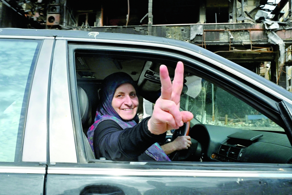 A Lebanese woman makes the victory sign as residents return to their neighbourhood in Beirut's southern suburbs after a 10-day ceasefire with Israel comes into effect. — AFP
