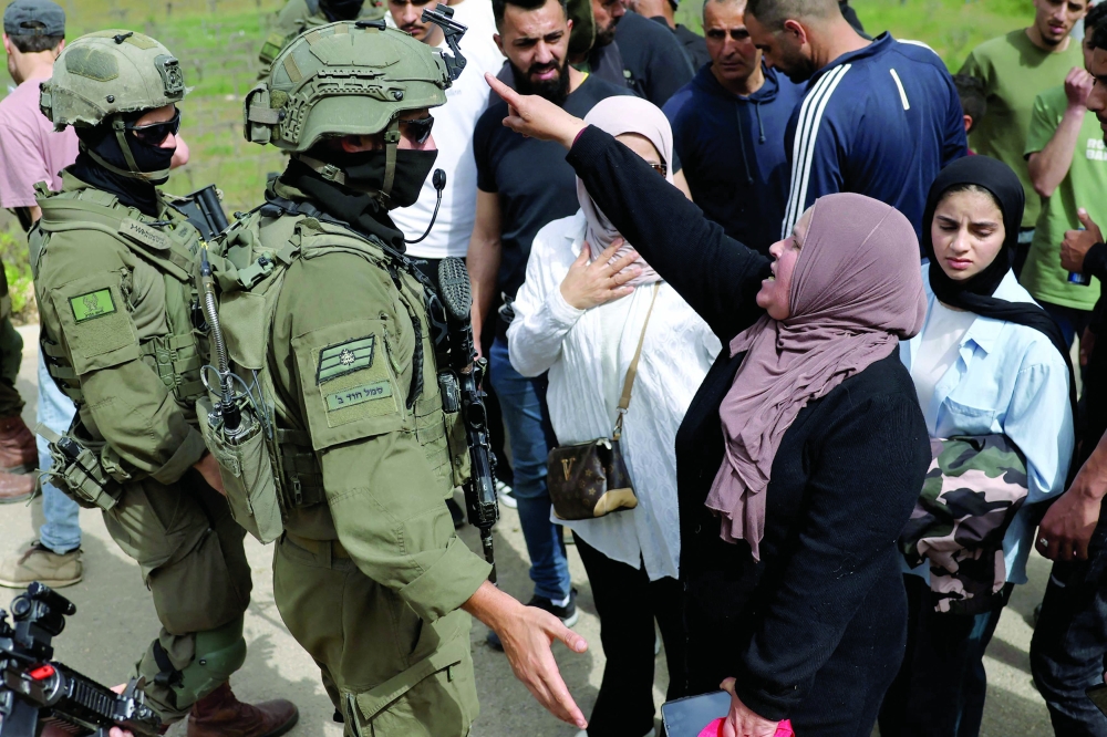 A Palestinian woman reacts towards Israeli security forces as they forcibly remove Palestinians near Halhoul, south of the Israel-occupied West Bank city of Hebron, on Friday. — AFP