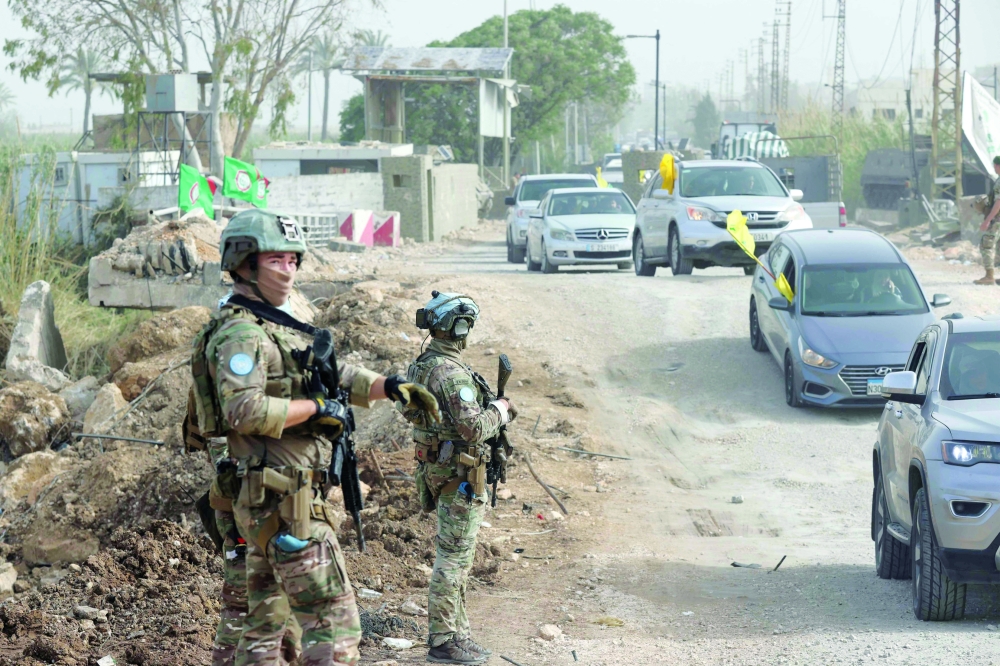 A French contingent of the United Nations Interim Force in Lebanon (UNIFIL) patrols the area as displaced residents waving Hezbollah flags make their way back to their homes on a makeshift road, built at the site where the Qasmieh bridge was destroyed in Israeli strikes, in the southern Lebanese area of Al-Qasmiyeh on April 18, 2026. Israel and Lebanon agreed to a 10-day ceasefire on April 16 in order to negotiate an end to six weeks of war between Israel and the Iran-backed group Hezbollah. The conflict saw massive Israeli airstrikes across Lebanon and also a ground invasion in the south. (Photo by MAHMOUD ZAYYAT / AFP)

