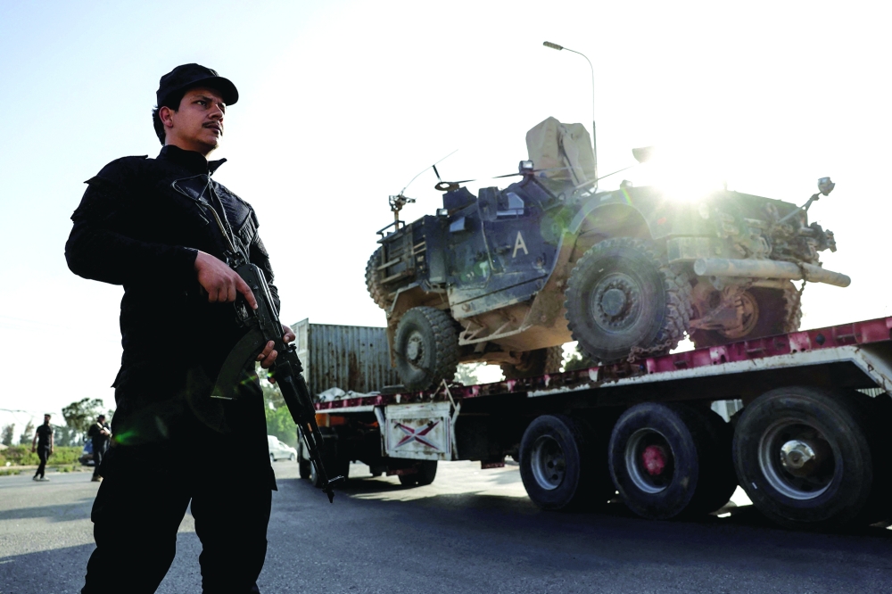 Syrian security stands guard as a convoy of US military equipment is transported, in Damascus. — AFP