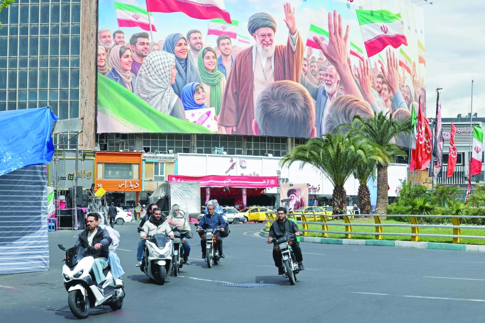 Motorists ride past a giant billboard of slain Iranian supreme leader Ayatollah Ali Khamenei at the Valiasr Square in Tehran. — AFP