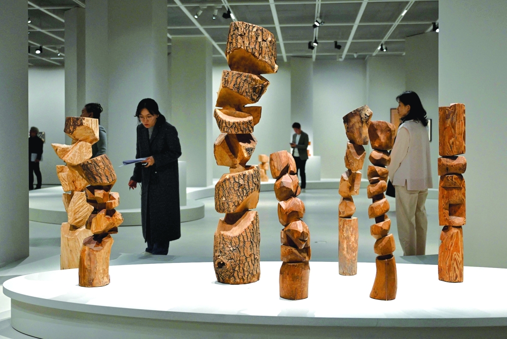 This picture taken on March 11, 2026, shows visitors looking at works of South Korean sculptor Kim Yun Shin in her retrospective exhibition, titled "Two Be One", at Hoam Museum of Art in Yongin. In her 90s, South Korean sculptor Kim Yun Shin still wields a chainsaw with quiet focus, refining a craft she honed over decades spent far away from home. - TO GO WITH AFP 