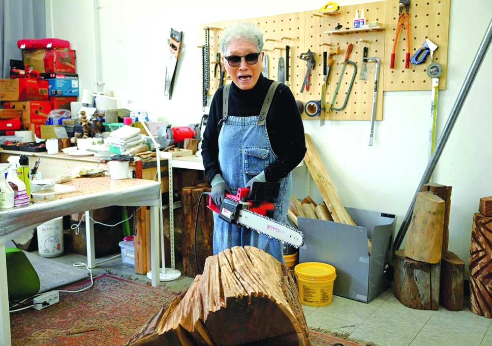 This picture taken on March 4, 2026, shows South Korean sculptor Kim Yun Shin using a chainsaw to create a work at her studio in Paju. In her 90s, South Korean sculptor Kim Yun Shin still wields a chainsaw with quiet focus, refining a craft she honed over decades spent far away from home. - TO GO WITH AFP STORY  SKorea-Art BY Claire LEE