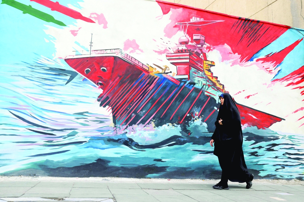 A woman walks past an anti-US and anti-Israel mural, in Tehran. — AFP