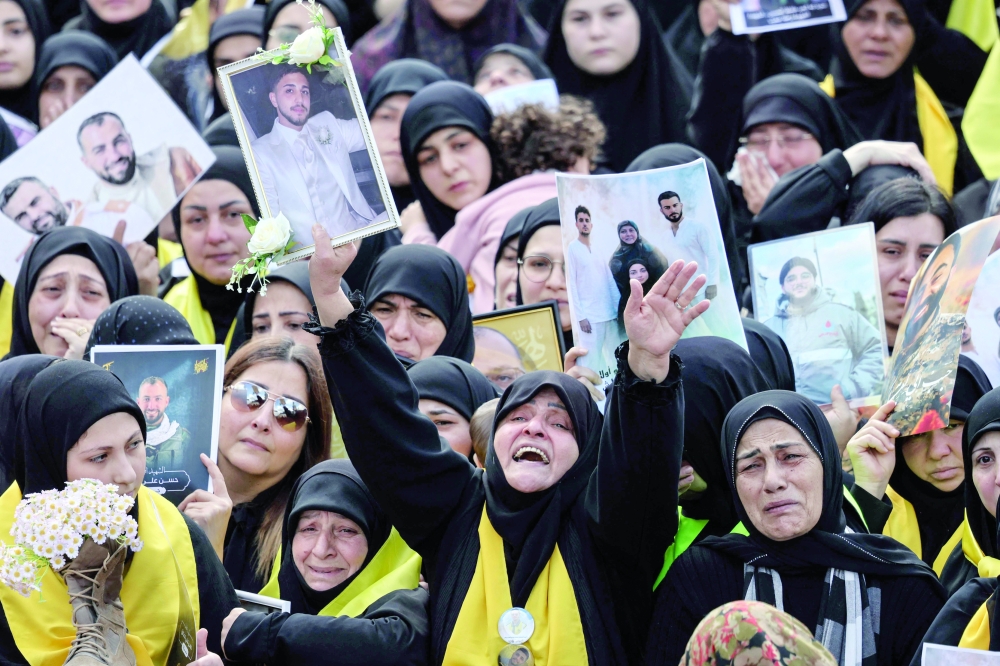 Mourners hold up portraits of killed ones during a mass funeral procession in the southern Lebanon. — AFP