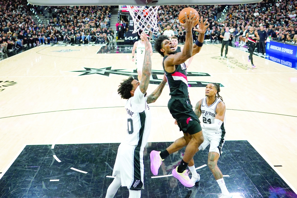 Portland Trail Blazers guard Scoot Henderson (0) drives between forward Julian Champagnie (30) and guard Devin Vassell (24) during the first half of game two of the first round of the 2026 NBA Playoffs against the San Antonio Spurs at Frost Bank Center. — Imagn Images