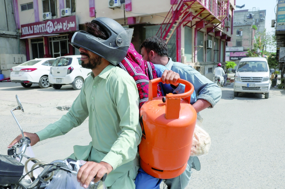 Men carry a gas cylinder as they ride on a motorbike in Islamabad on Thursday. — Reuters