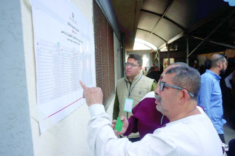 A Palestinian man looks at a list of candidates at a polling station in Gaza Strip on Saturday. — AFP