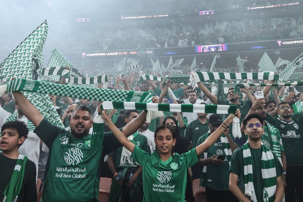 Al Ahli fans, women and men, hold up the team colours during the final  
