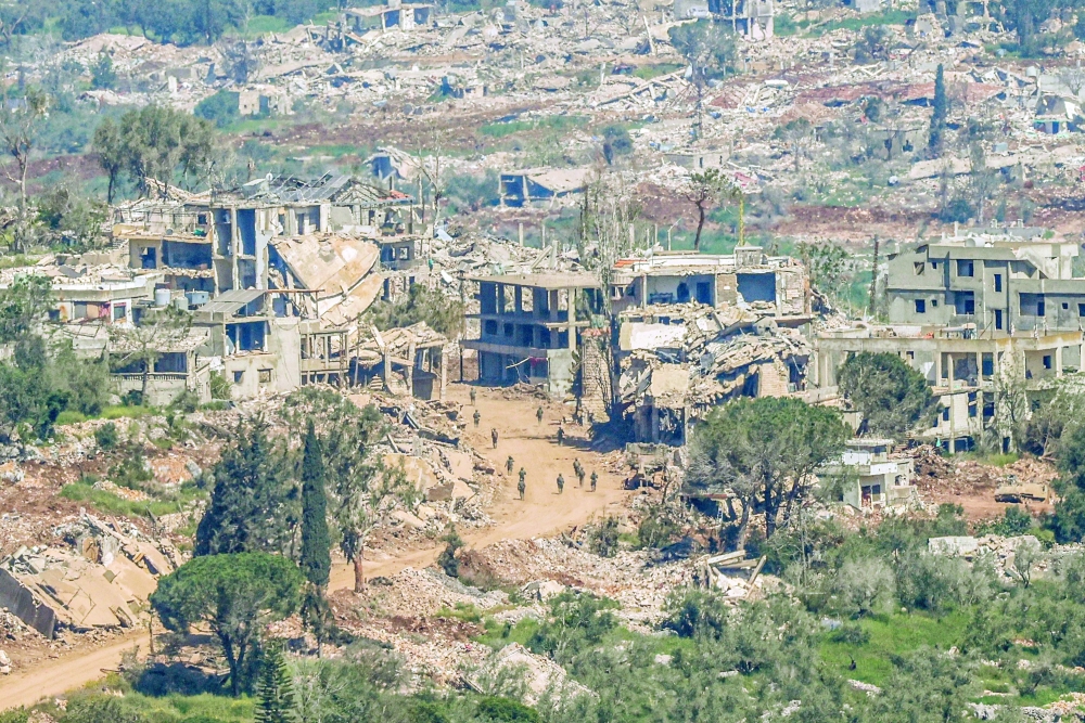 Israeli soldiers walk along the road between destroyed houses in southern Lebanon. — AFP