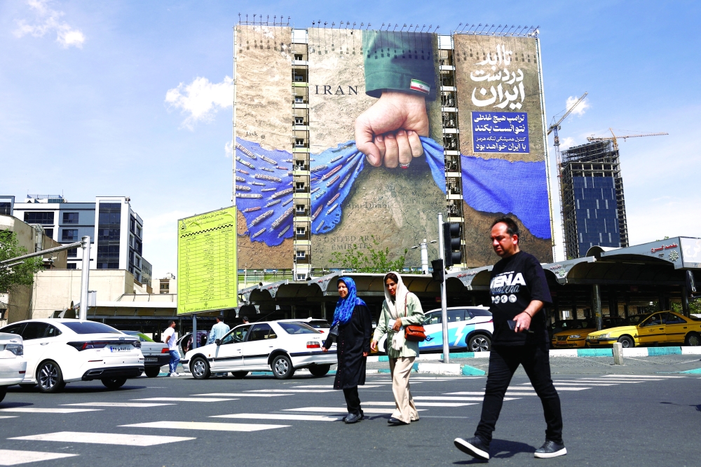 People walk past a billboard with a graphic design about the Strait of Hormuz on a building, in Tehran. — Reuters
