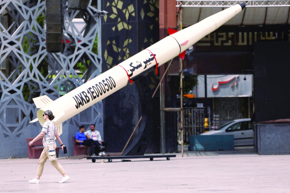 A woman walks next to a symbolic mock-up of an Iranian missile in Tehran, Iran, on Monday. — Reuters