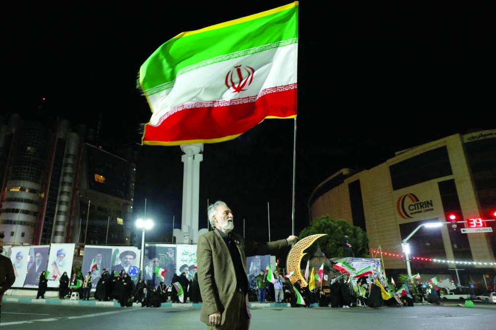 A man holds an Iranian flag during a rally in support of Iran's supreme leader Ayatollah Mojtaba Khamenei, in Tehran. — AFP
