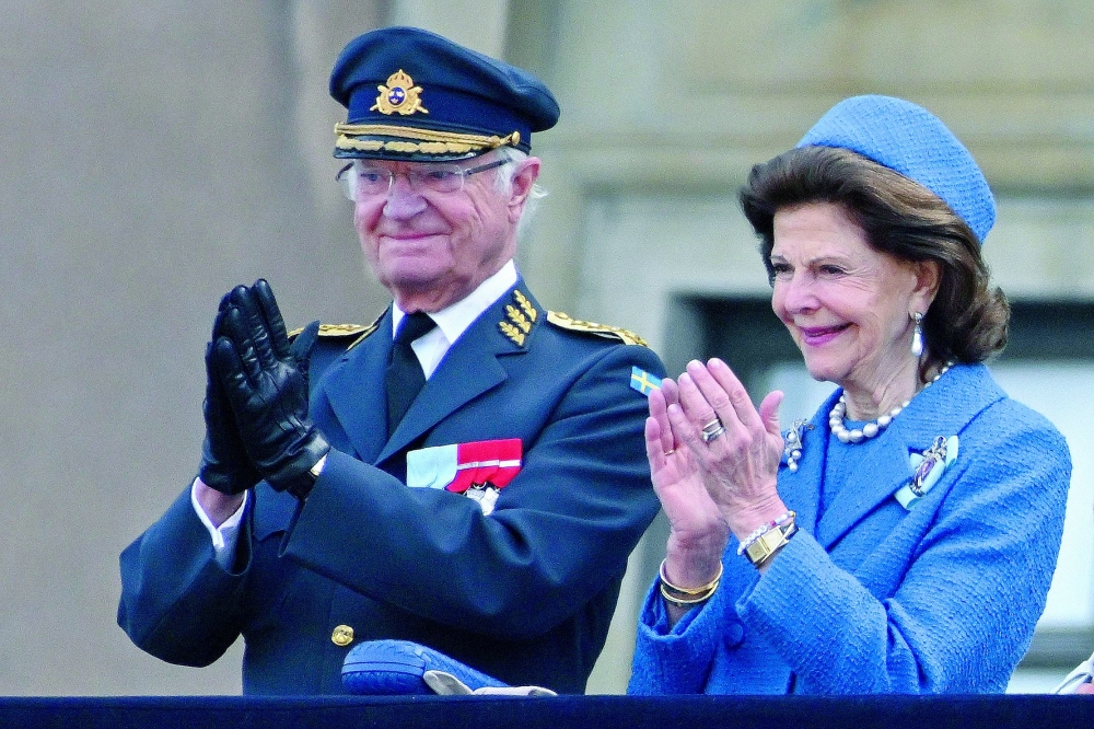 Sweden's King Carl XVI Gustaf and Sweden's Queen Silva applaud as members of the Swedish Armed Forces pay tribute to the King at the Outer Courtyard of the Royal Palace in Stockholm during celebrations to mark the 80th birthday of Sweden's King Carl XVI Gustaf. — AFP