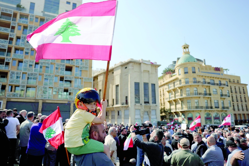 A child waves a Lebanese flag while residents, and inhabitants of the devastated southern Lebanese border villages protest against the destruction of their villages and being prevented from returning by order of the Israeli army, at Martyrs’ Square in central Beirut. — AFP
