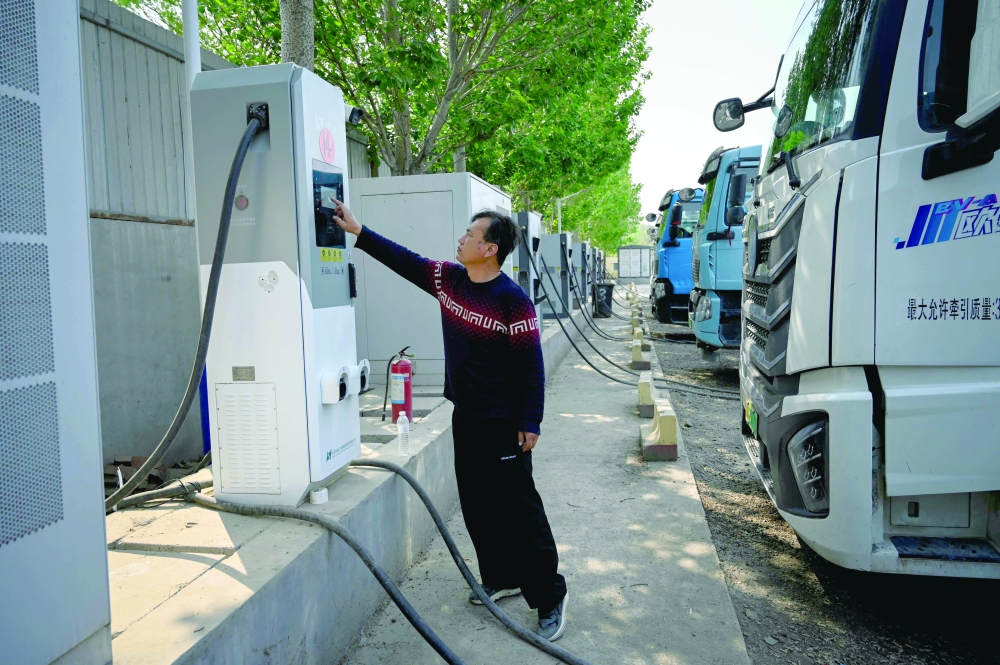 A driver checking the status of his electric truck at a charging station in Beijing. — AFP
