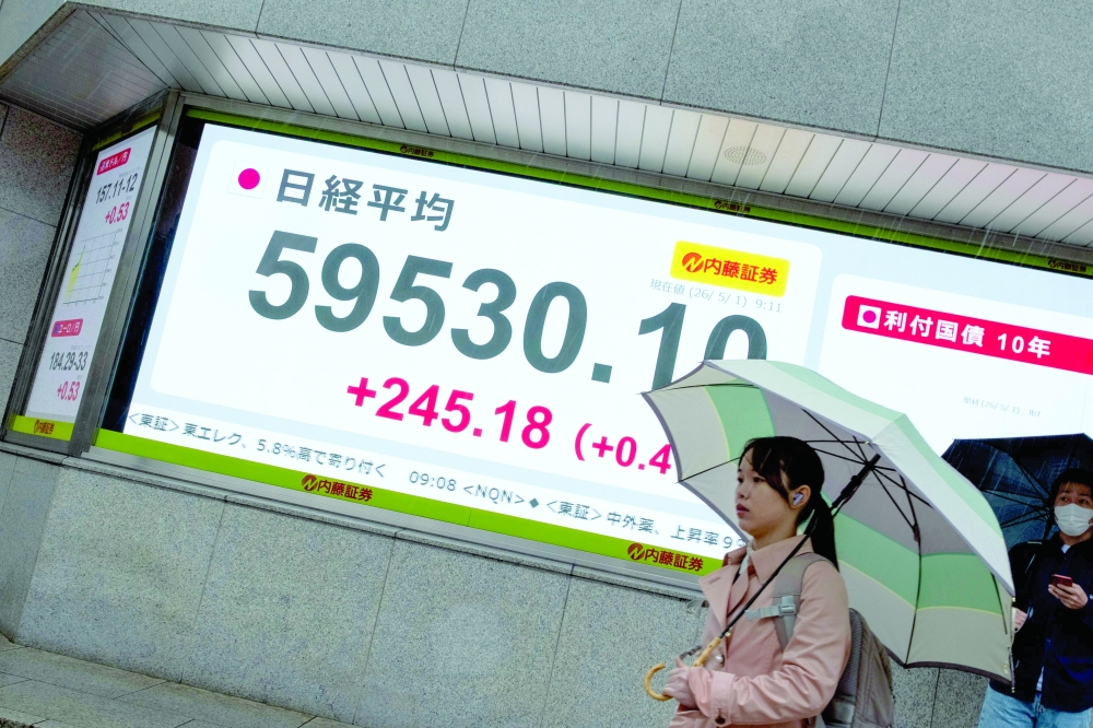 A woman walks past an electronic quotation board displaying the Nikkei Stock Average on the Tokyo Stock Exchange along a street in Tokyo. — AFP
