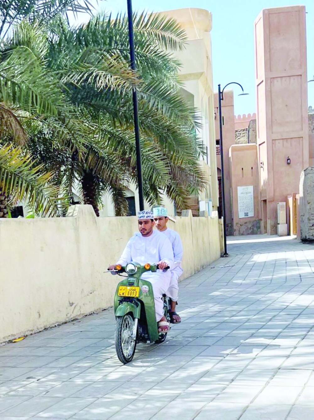 Young boys share a scooter ride through the narrow lanes of Nizwa