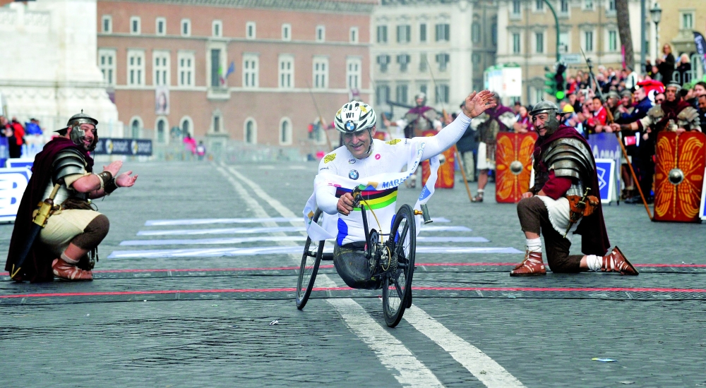 Former driver and paracyclist Alex Zanardi celebrates as he crosses the fininsh line of the 20th Marathon of Rome on March 23, 2014. — AFP