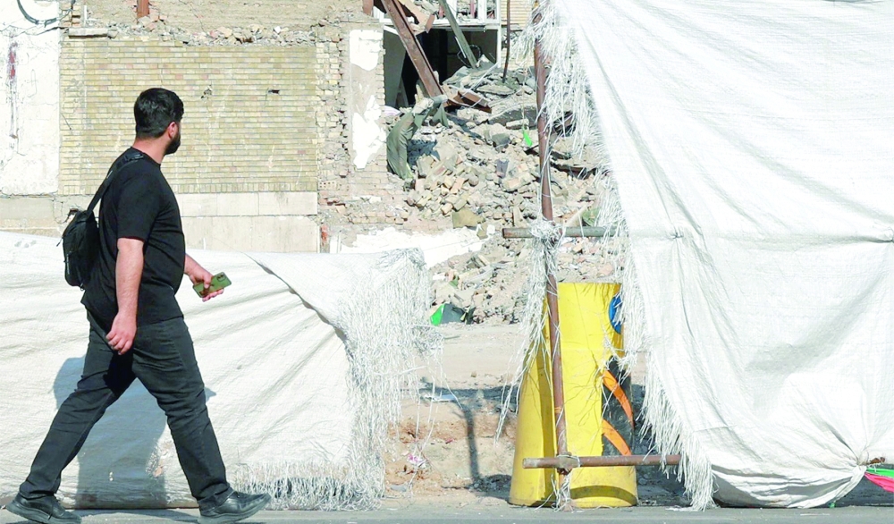 A man walks past the Alameh Tabatabaei high school, which was destroyed by a US-Israeli air strike during the war, in Tehran, on Sunday. — AFP