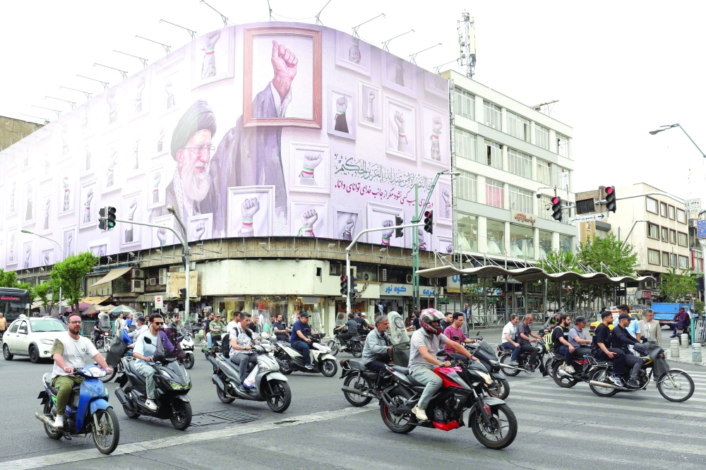 Iranians drive past a huge billboard carrying the image of the late Iranian supreme leader Ayatollah Ali Khamenei, in a street in Tehran. — AFP