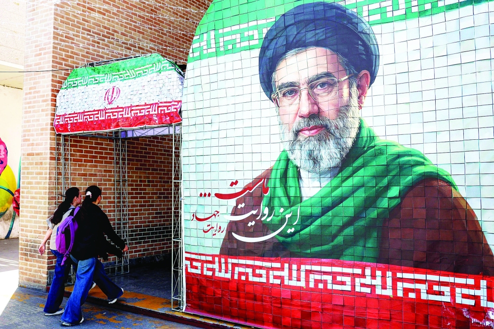 Women walk past a banner depicting Iran's supreme leader Ayatollah Mojtaba Khamenei along a street Tehran. — AFP