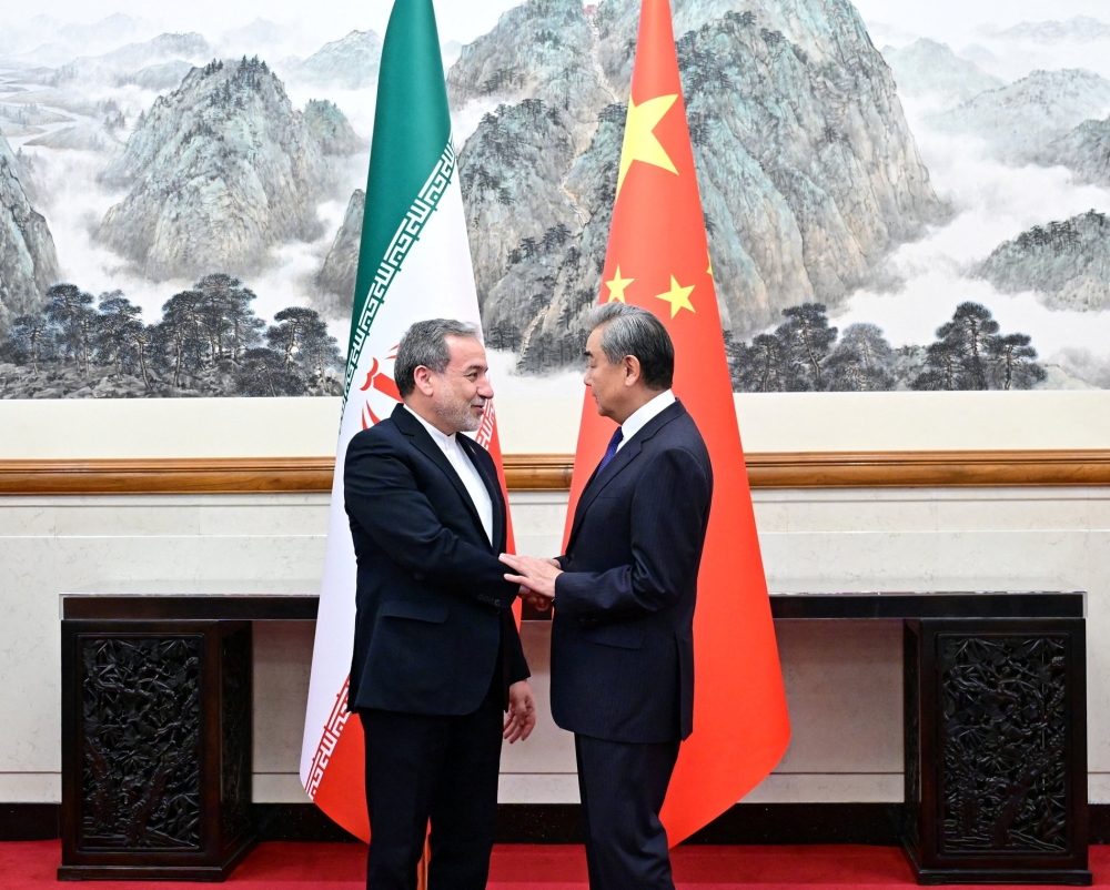 Chinese Foreign Minister Wang Yi and Iranian Foreign Minister Abbas Araqchi shake hands in Beijing