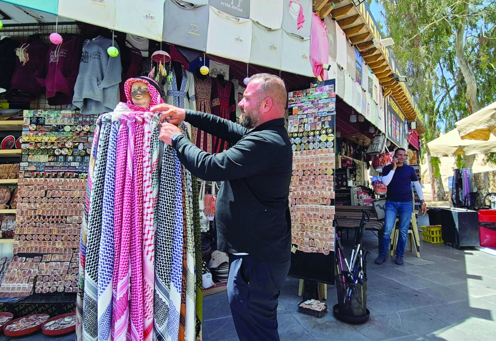 Jordanian vendor Khalid al Saidat adjusts scarves while waiting for customers at his souvenirs shop near the Guests Center at the ancient Nabatean city of Petra. — AFP