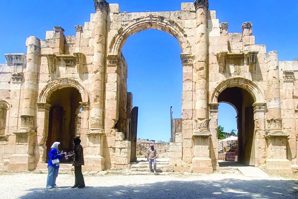 People stand before the Roman-era South Gate, was built in honour of the Roman Emperor Hadrian on the occasion of his visit circa AD 130, is pictured at the Roman ruins of Jerash in northern Jordan. - AFP