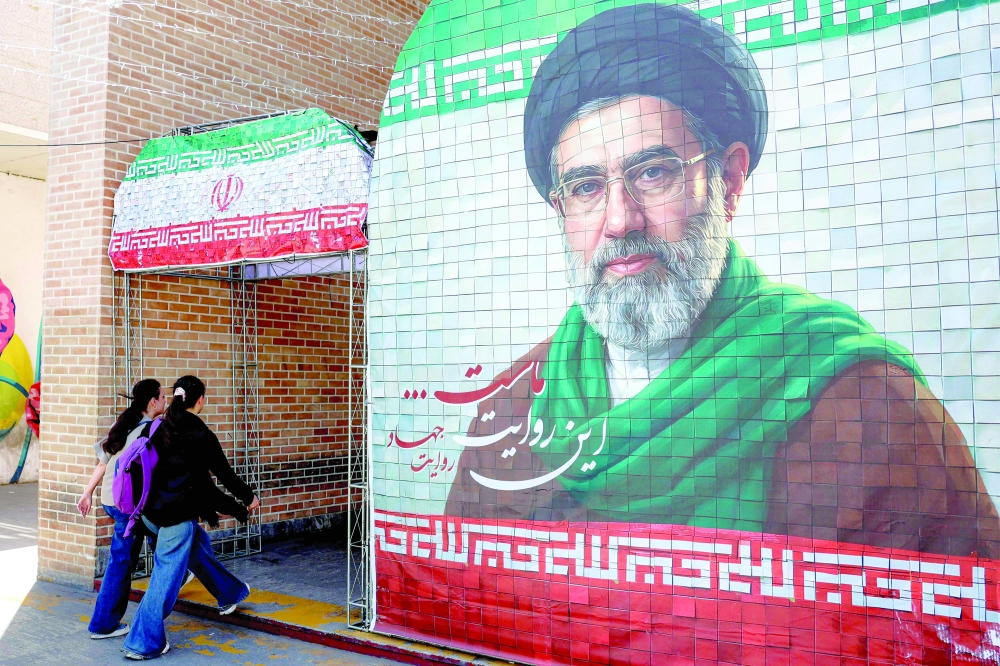 Women walk past a banner depicting Iran's current supreme leader Ayatollah Mojtaba Khamenei along a street Tehran on May 6, 2026. 