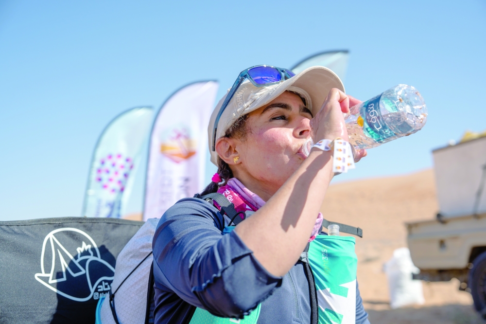 Nagma al Rahbi hydrating mid-race at the 2026 Oman Desert Marathon