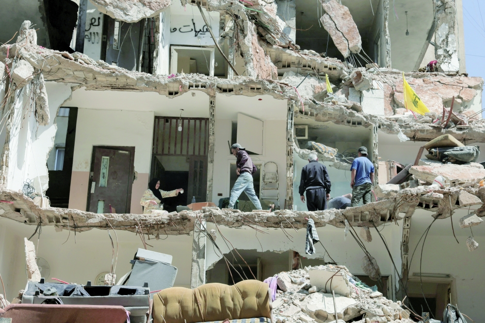 Ali Soueidan from southern Lebanon, looks at people cleaning his damaged house in the southern suburbs of Beirut. — Reuters