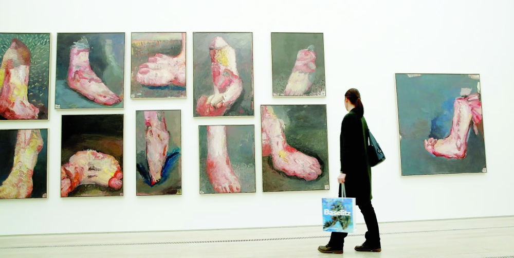 A woman stands in front of the paintings 'P D Feet, 1960-63' and 'P D Foot-Interior, 1963' (R) of German artist Georg Baselitz. — Reuters