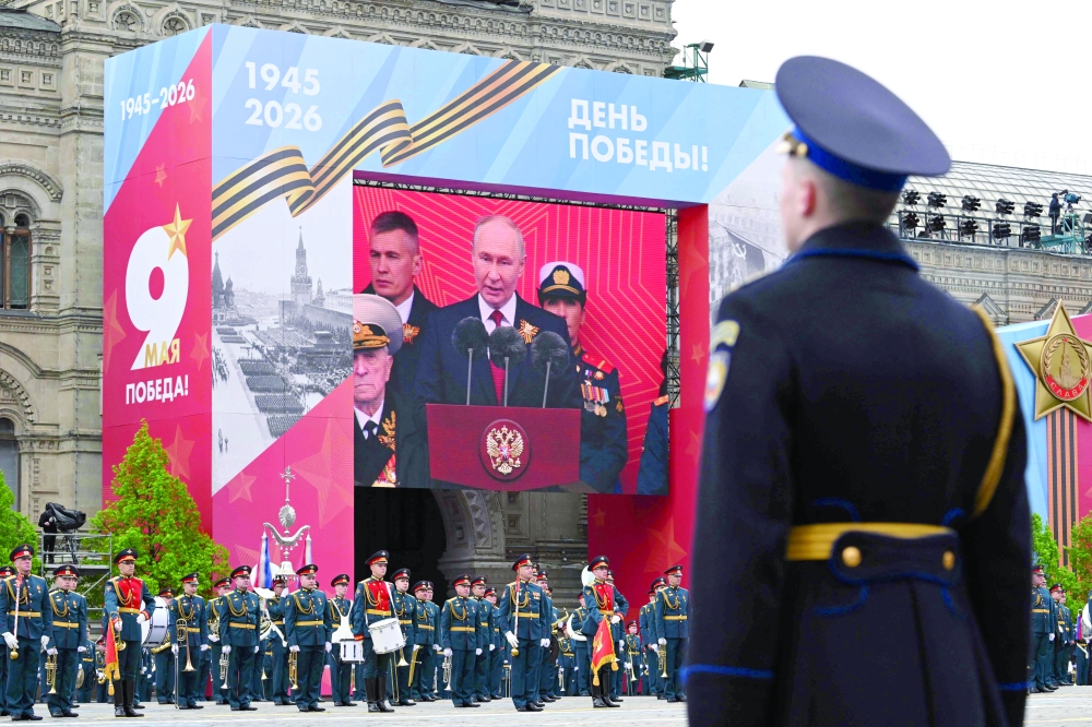 Members of a military band stand next to a screen broadcasting Russia's President Vladimir Putin's address during the Victory Day military parade in Moscow. — AFP