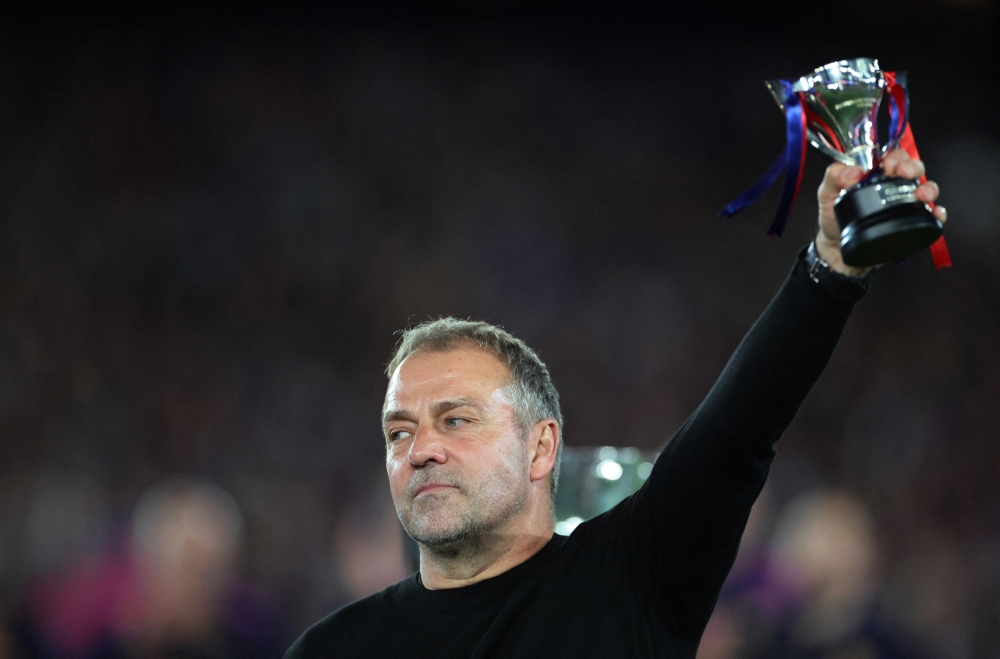  
FC Barcelona coach Hansi Flick celebrates with a trophy after winning the LaLiga  