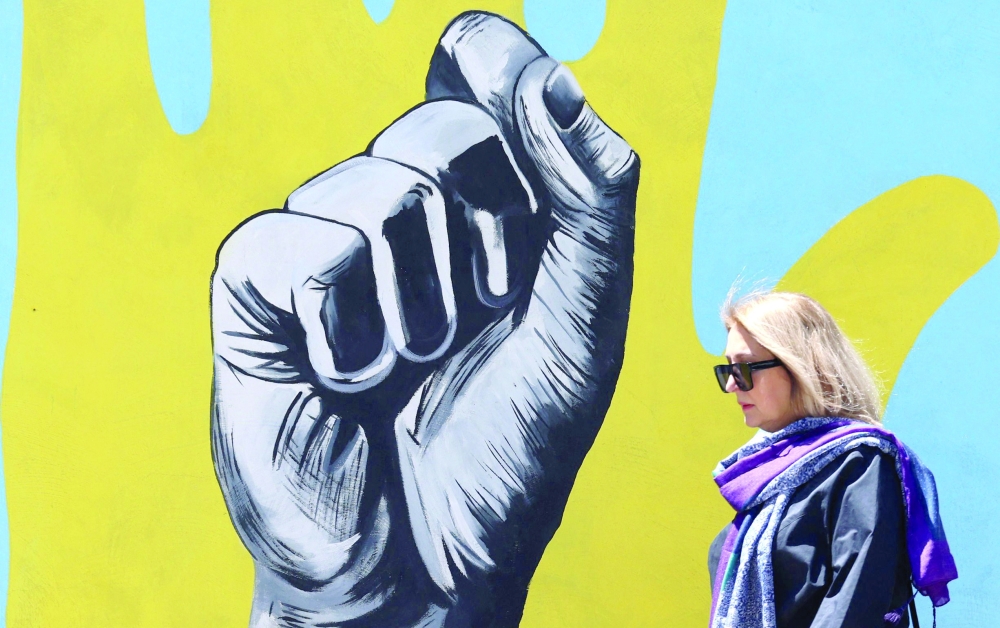 An Iranian woman walks past a mural painted on a wall in Tehran on Monday. - AFP