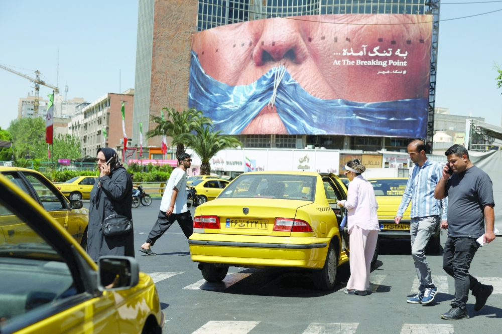 People walk past an anti-US billboard in Tehran. — Reuters