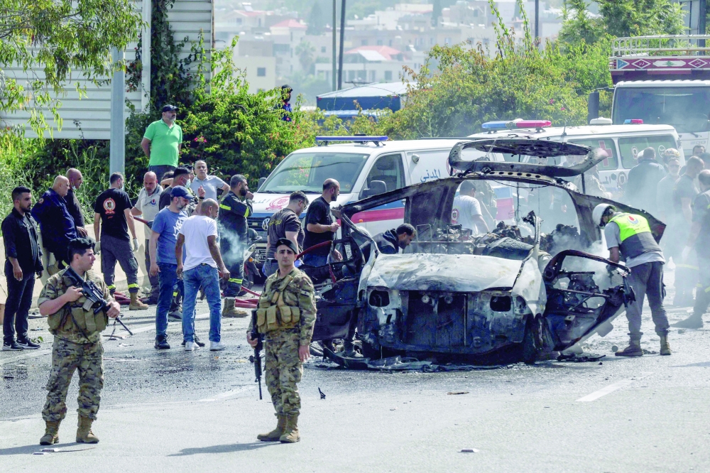 First responders intervene on a vehicle targeted by an Israeli drone strike on a highway near the town of Jiyeh, south of Beirut. — AFP