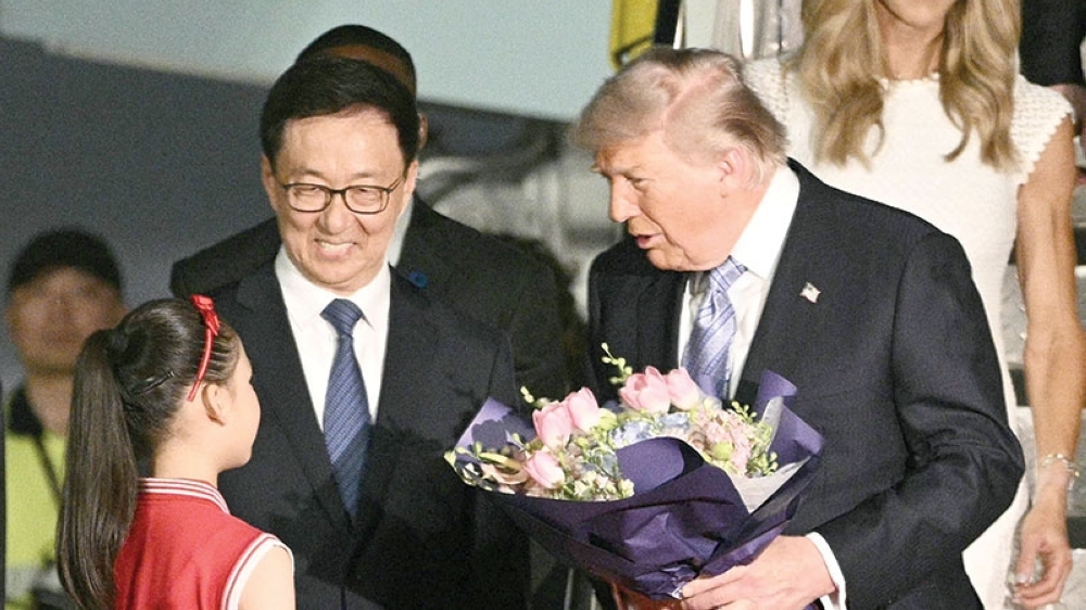 US President Donald Trump receives flowers upon arriving at Beijing Capital Airport in Beijing on Wednesday. - AFP
