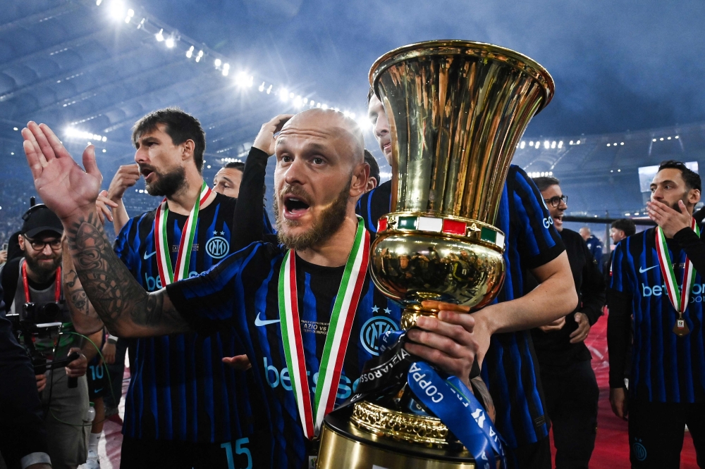 Inter Milan's Italian defender #32 Federico Dimarco holds the trophy of the Italian Cup (Coppa Italia) and celebrates with teammates  
