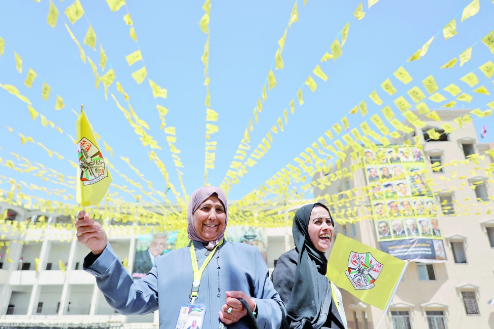 Palestinian women wave flags as they attend the opening of the Fatah party's eighth general conference at Al Azhar University in Gaza City. - AFP
