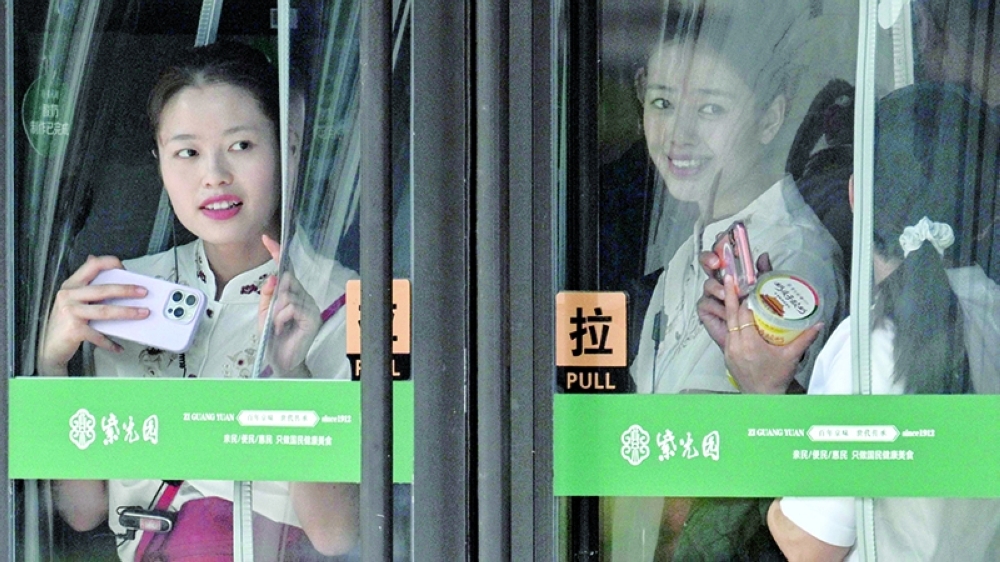Women in a mall try to watch US President Donald Trump's motorcade pass by in Beijing on Thursday. — AFP