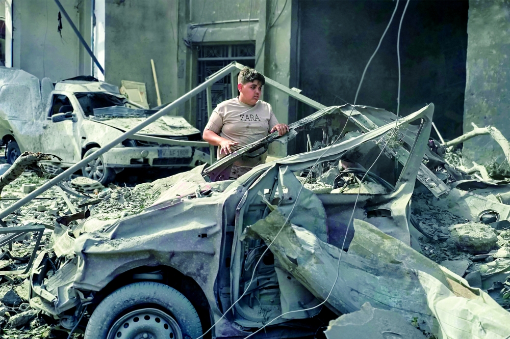 A boy inspects a destroyed vehicle following overnight Israeli bombardment on Lebanon's southern city of Tyre. — AFP 