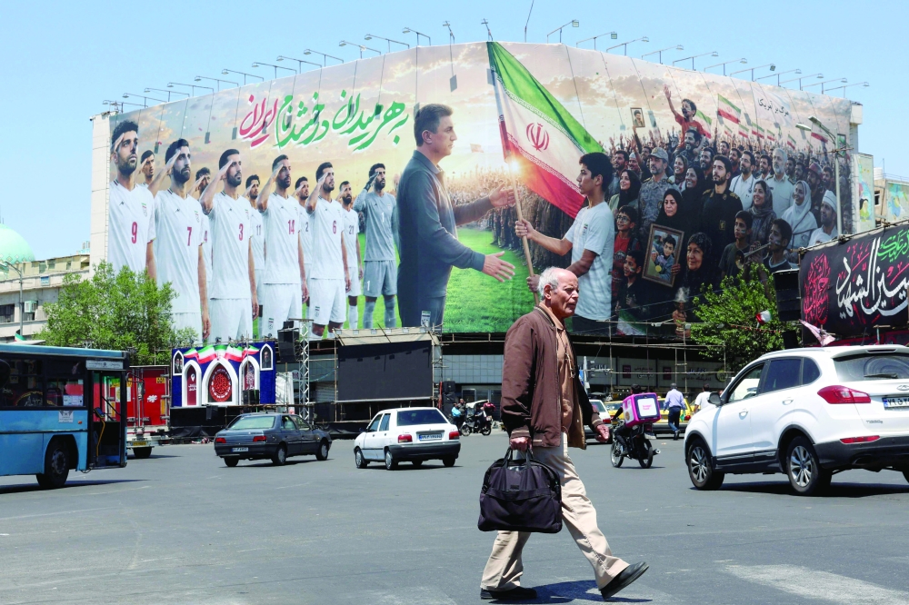 An Iranian man walks past a huge billboard supporting Iran’s national football team in the upcoming 2026 World Cup, installed on a building at Enghelab Square in Tehran. — AFP