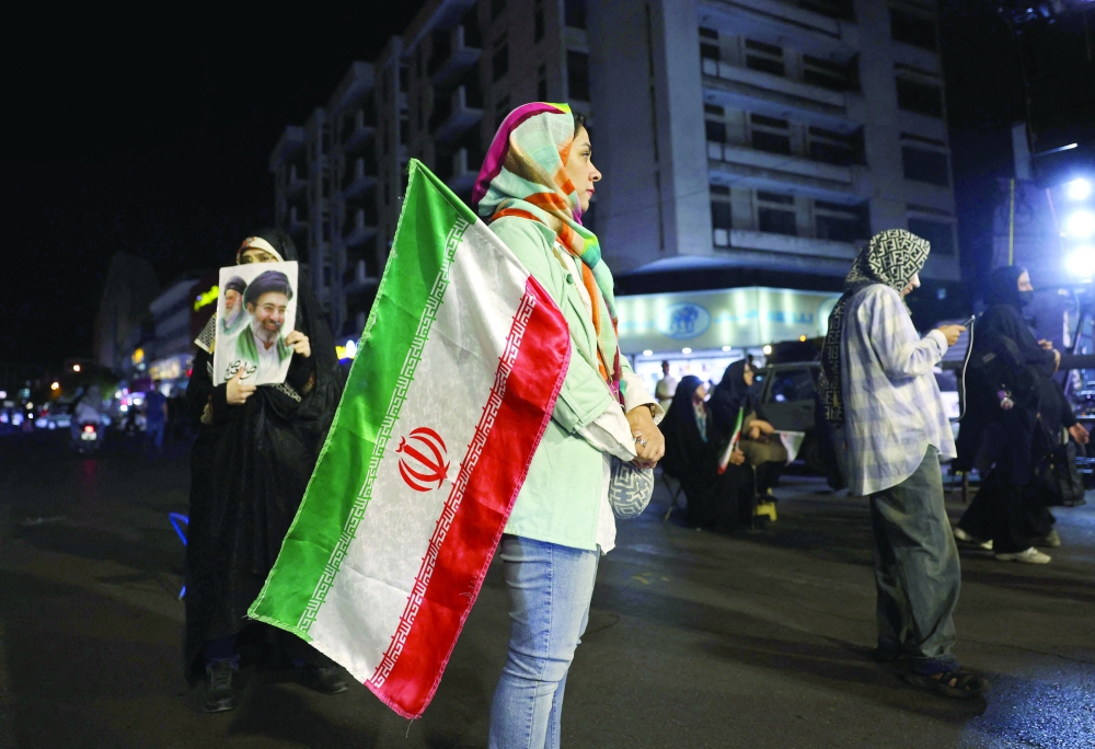 A woman holds Iran's national flag during a protest at the Hafte Tir Square in Tehran on Monday. - AFP