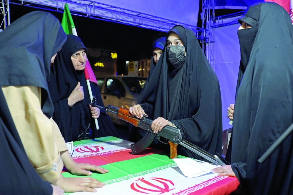 An Iranian military personnel (C) educates women about how to use a gun at a booth in Hafte Tir Square, in Tehran. — AFP